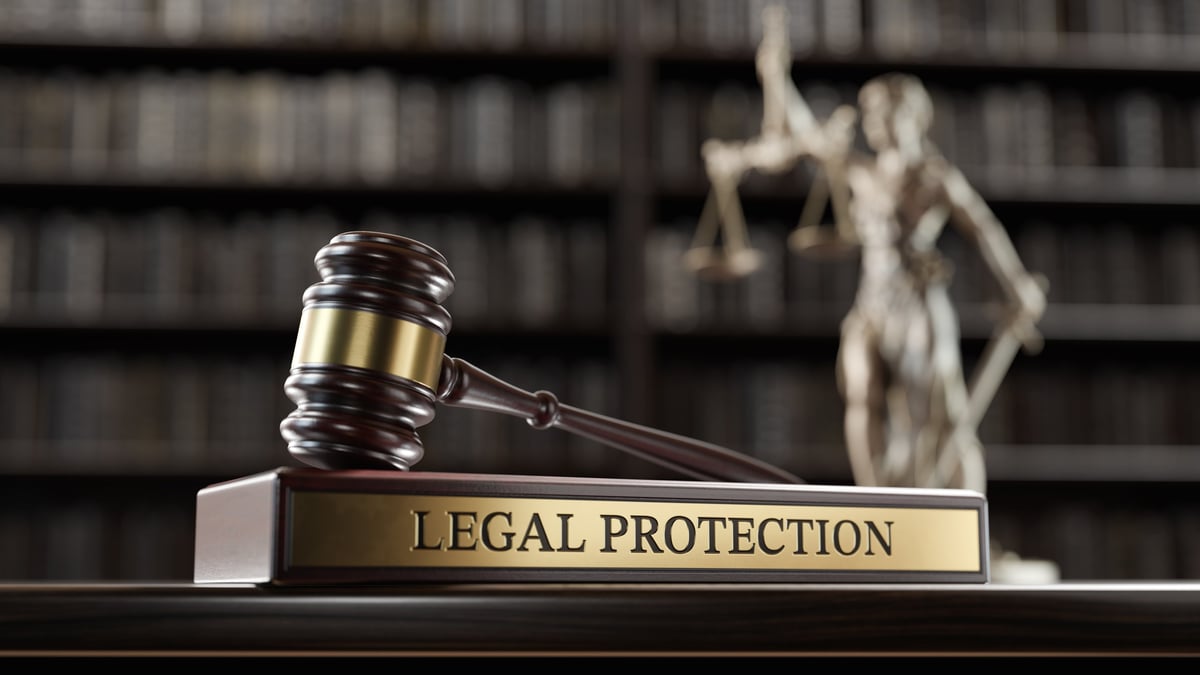 Judge's gavel and Themis statue on wooden stand with books in background