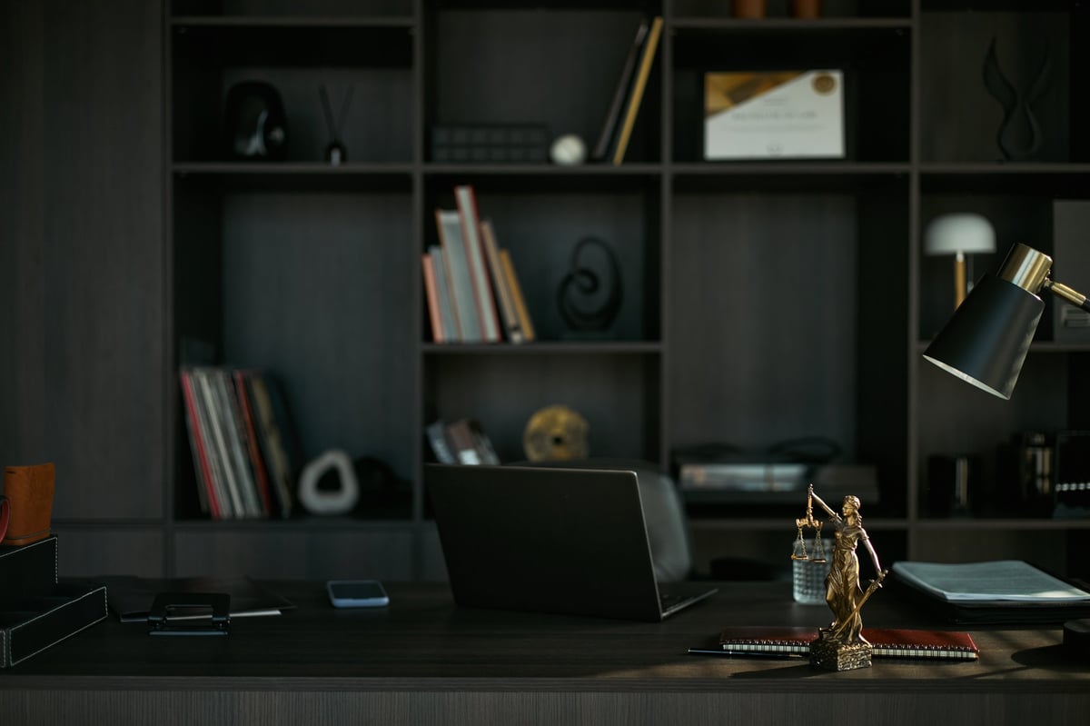 Attorney's office desk with legal files and Lady Justice statue